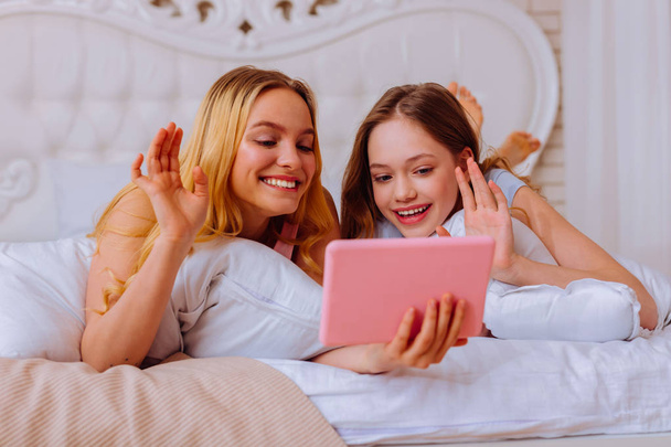 Daughters waving their hands while having video chat with parents - Foto, immagini