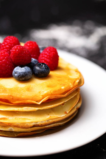 Closeup photo of plate of pancakes, blueberries, raspberries and powdered sugar. - Photo, Image