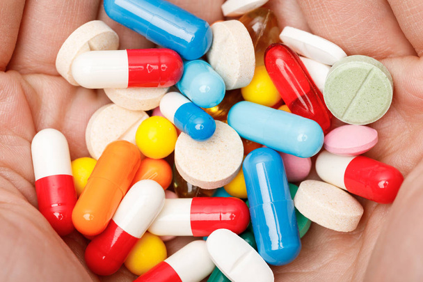 Gedeeltelijke mening van vrouw die kleurrijke pillen in handen houdt - Foto, afbeelding