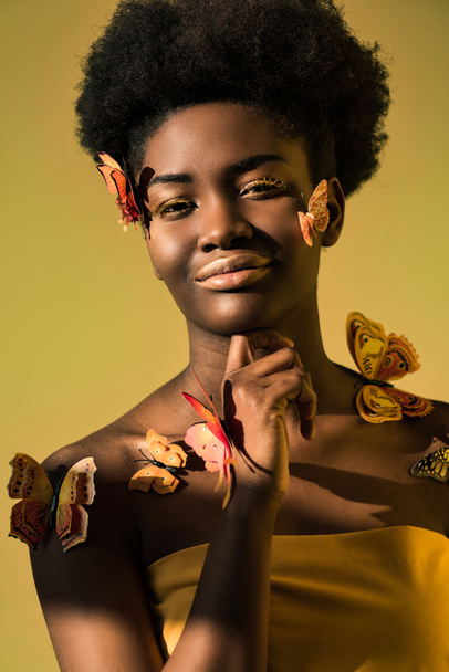 Joyful african american with butterflies looking at camera isolated on brown - Foto, imagen