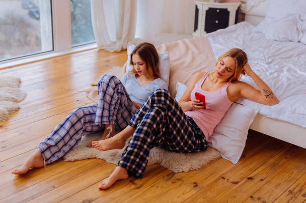 Sisters feeling bored with each other using social media - Foto, imagen