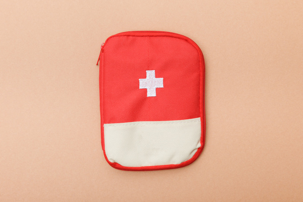 Top view of red first aid kit bag on brown surface - Фото, изображение