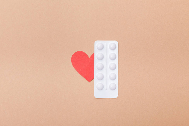 Pohled na puchýř s pilulkami a papírovým srdcem izolovaným na hnědém - Fotografie, Obrázek