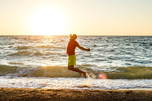 Imagem de homem feliz pulando na praia
 - Foto, Imagem