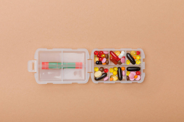 Top view of container with colorful pills on brown surface - Foto, Imagem