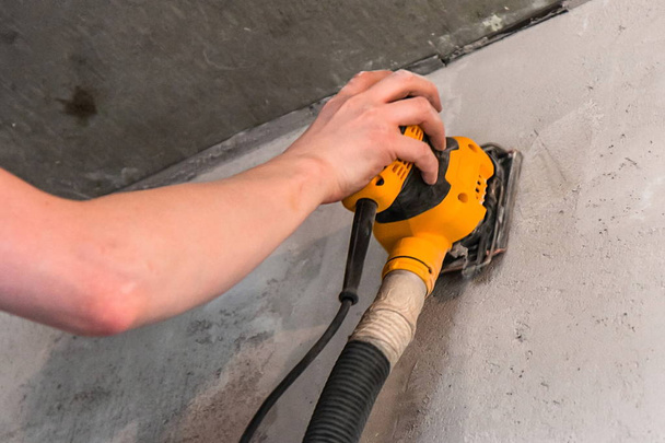 sanding a wall with a mechanical tool - Foto, Imagem