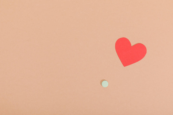 Top view of paper heart and pill on brown surface - Foto, Imagem