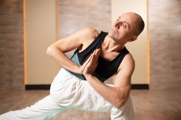 Man looking to side , practicing yoga standing on blue mat. - Fotó, kép