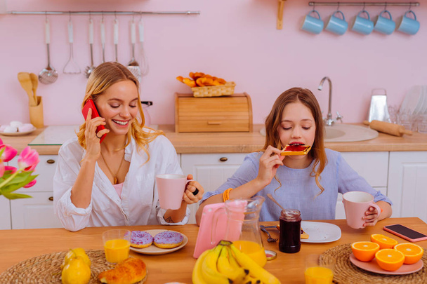 Older sister calling parents while having breakfast with sibling - Photo, image