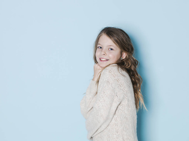 pretty and cool girl wearing wool sweater posing in front of blue background  - Photo, image