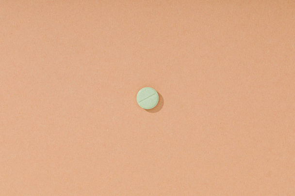 Top view of green pill on brown surface - 写真・画像