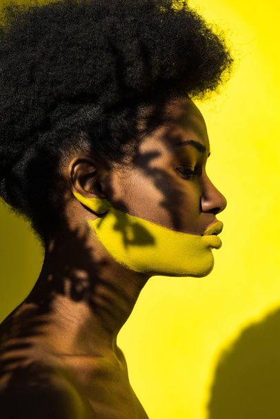 Side view of african american woman with body art on yellow - Φωτογραφία, εικόνα