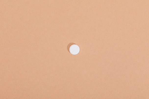 Top view of white pill on brown surface - Фото, изображение