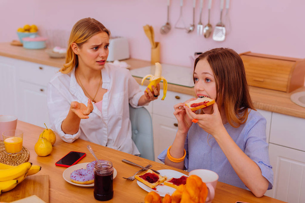 Menina de olhos azuis comendo torradas demais com geléia para o café da manhã
 - Foto, Imagem