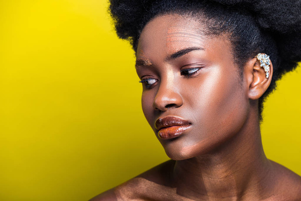 Mujer afroamericana atractiva pensativa con manguito en amarillo
 - Foto, Imagen