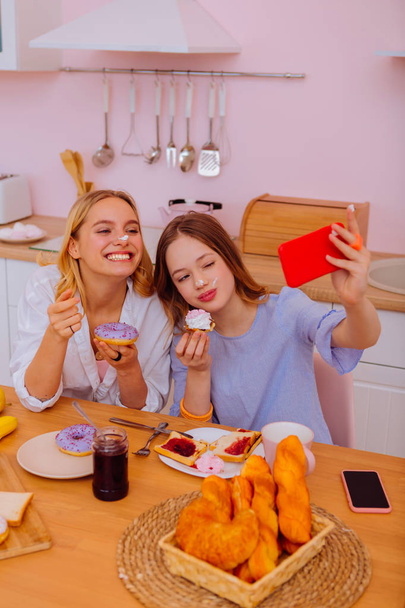 Meisje rood smartphone houden terwijl het maken van de selfie met broer/zus - Foto, afbeelding
