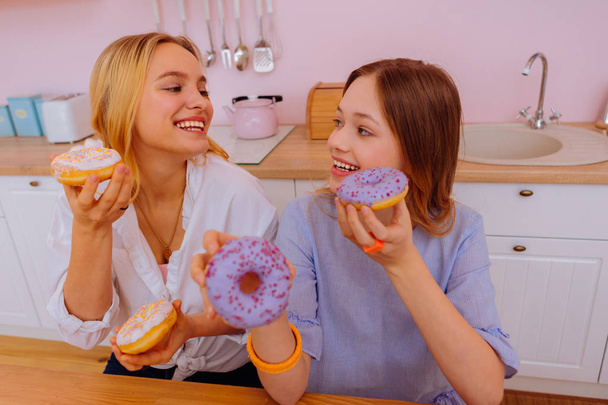 Beaming sisters having some sweet doughnuts for breakfast - Fotoğraf, Görsel