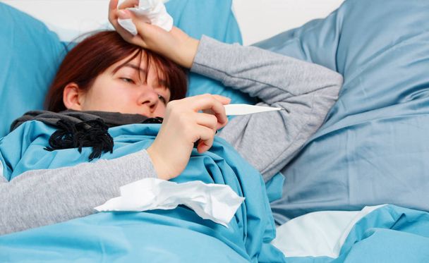 Photo of sick woman with thermometer lying on bed. - Photo, Image