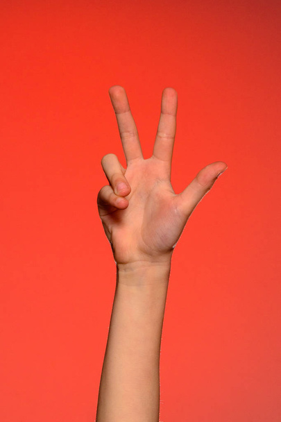 Αρσενικό χέρι δείχνει τρία δάχτυλα απομονώνονται σε κόκκινο φόντο - Φωτογραφία, εικόνα