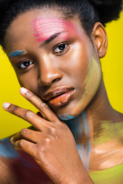 Charming african american woman with colorful body art isolated on yellow - Foto, immagini