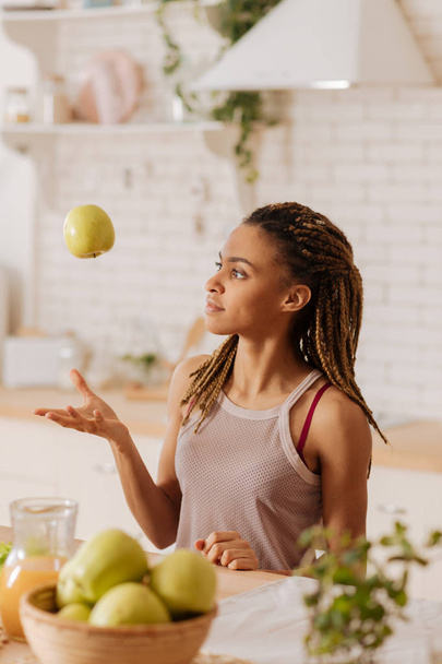 Slim woman wearing sport top throwing apple into air - Photo, image