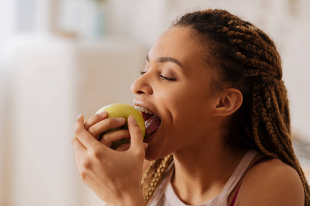 Красивая молодая женщина кусает хорошее зеленое яблоко по утрам
 - Фото, изображение