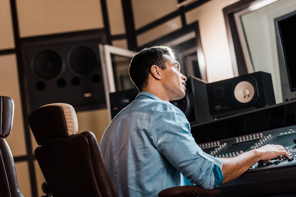 producteur sonore métissé attentif travaillant à la console de mixage en studio d'enregistrement
 - Photo, image