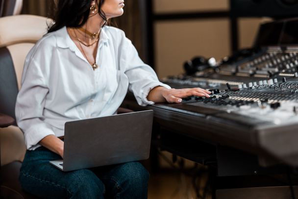 cropped view of sound producer working at mixing console and using laptop  - Photo, Image