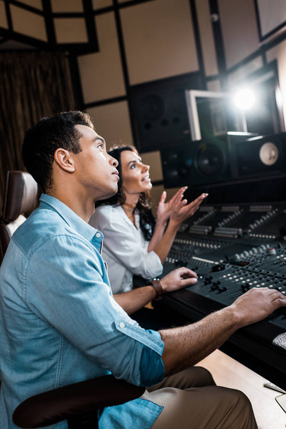レコーディングスタジオでミキシングコンソールで働くサウンドプロデューサーの選択的な焦点 - 写真・画像