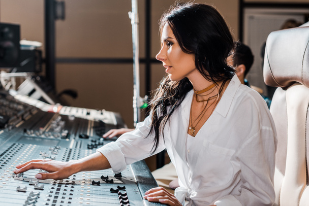 kaunis tiivistetty äänentuottaja työskentelee miksauskonsolilla äänitysstudiossa
 - Valokuva, kuva