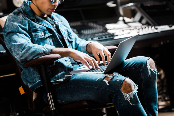 skoncentrowany producent dźwięku mieszane wyścigu przy użyciu cyfrowego laptopa w studiu nagraniowym - Zdjęcie, obraz