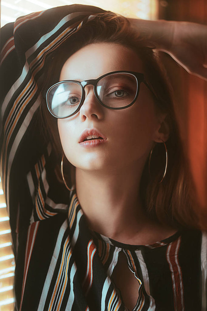 Bellezza sexy modello donna ritratto indossando occhiali. Donna elegante guardando la macchina fotografica negli occhiali neri, ragazza di bellezza di moda vicino alla finestra. Moderno tono blu. Ritratto
. - Foto, immagini