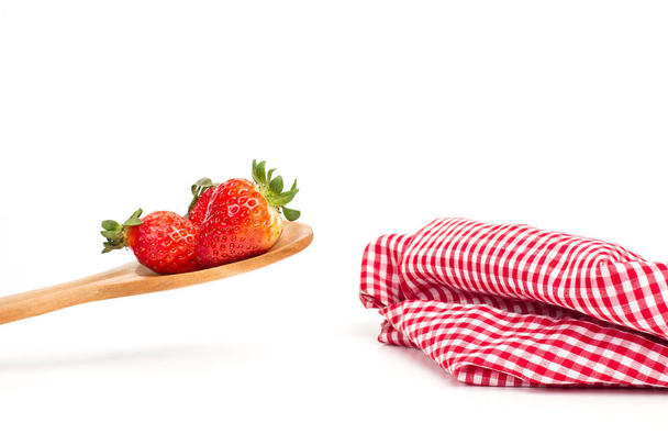 Fresas en una cuchara de madera con un mantel con mejillas blanco y negro
 - Foto, Imagen