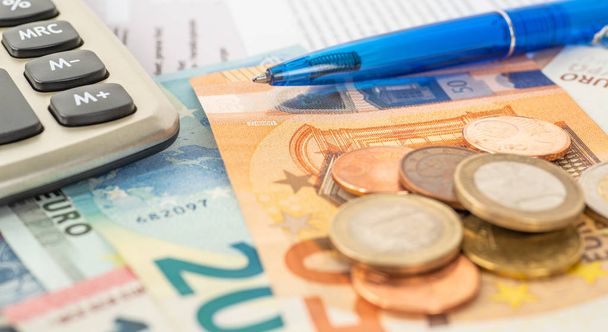 Una calculadora con billetes en euros y monedas en euros
 - Foto, imagen