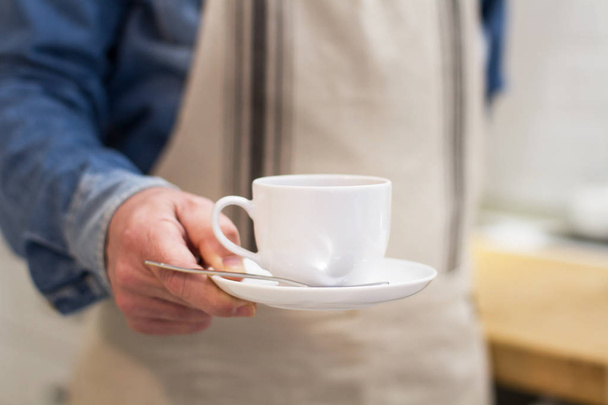 Un camarero con una taza de café en la mano en un bar
 - Foto, Imagen