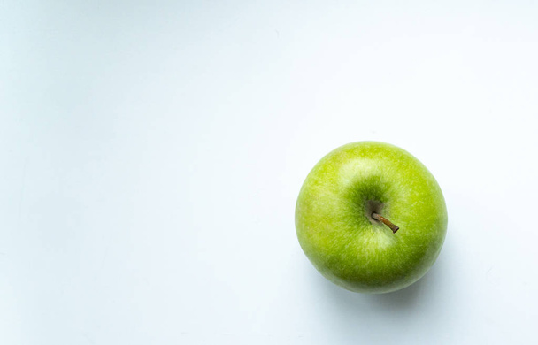 groene appel op een wit-blauwe achtergrond plaats voor een inscriptie - Foto, afbeelding