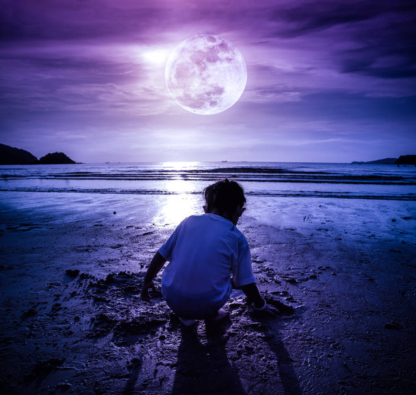 Ночное небо с супер луной. Девушка копается в песке. Концепция соединения детей с природой
.  - Фото, изображение