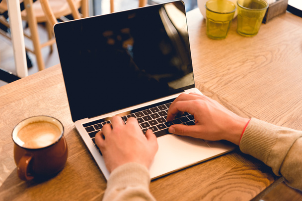περικομμένη προβολή του blogger χρησιμοποιώντας φορητό υπολογιστή με κενή οθόνη κοντά στο φλιτζάνι του καφέ  - Φωτογραφία, εικόνα
