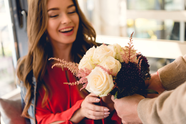 vue recadrée de petit ami donnant des fleurs à petite amie heureuse dans le café
  - Photo, image