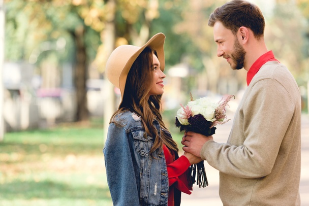 handsome man giving flowers to attractive girlfriend in hat  - Photo, Image