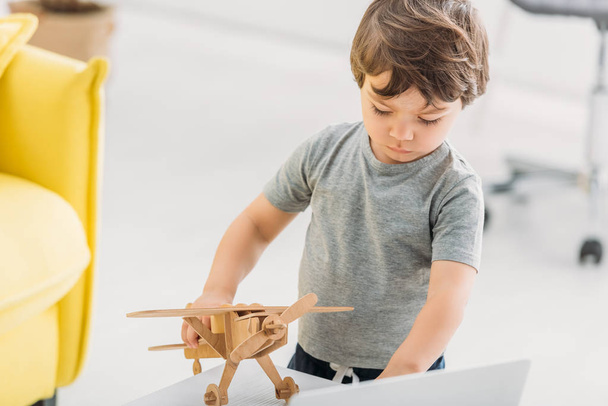 чарівний хлопчик грає з дерев'яною моделлю літака вдома
 - Фото, зображення