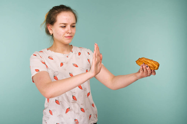 Pattanásos tini lány portréja hows keze megáll a finom sütemény - Fotó, kép