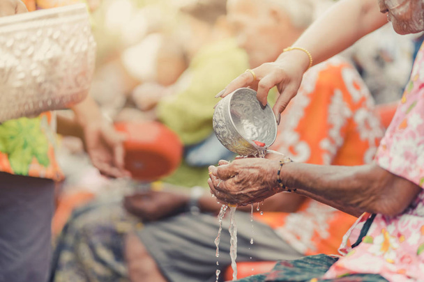 Thailänder feiern Songkran, indem sie Wasser gießen und älteren Senioren Girlanden schenken - Foto, Bild