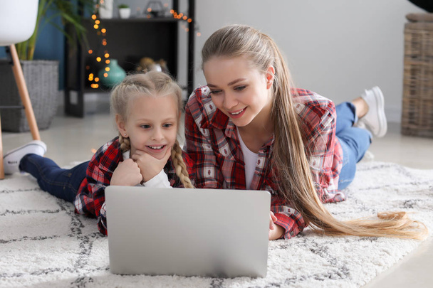 Jonge moeder met kleine dochter kijken cartoons thuis - Foto, afbeelding