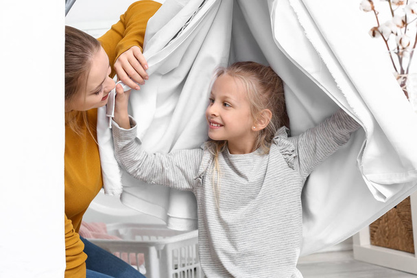 Nuori nainen ja hänen pieni tyttärensä leikkivät pyykkipäivänä
 - Valokuva, kuva