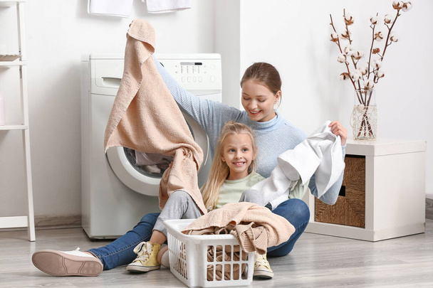 Jovem mulher e sua filha fazendo lavanderia em casa
 - Foto, Imagem