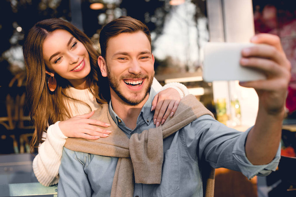 selective focus of happy man taking selfie with cheerful girlfriend  - Фото, изображение