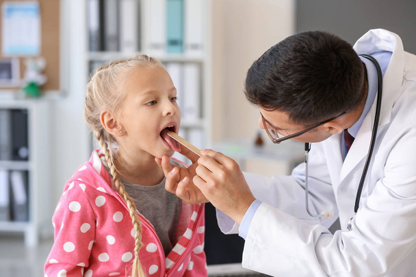 Педиатр осматривает маленькую девочку в клинике - Фото, изображение