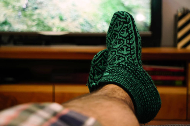 Snoozies tricotés sur le pied de l'homme regarder la télévision froid à la maison
 - Photo, image