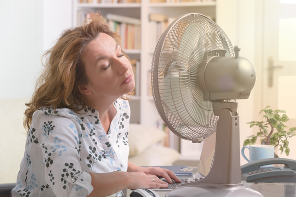 Mujer sufre de calor en la oficina o en casa
 - Foto, Imagen